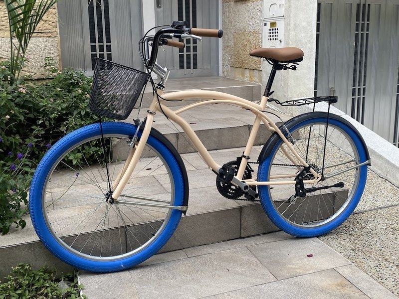 Bicicleta urbana personalizada color crema con llantas azules y canasta